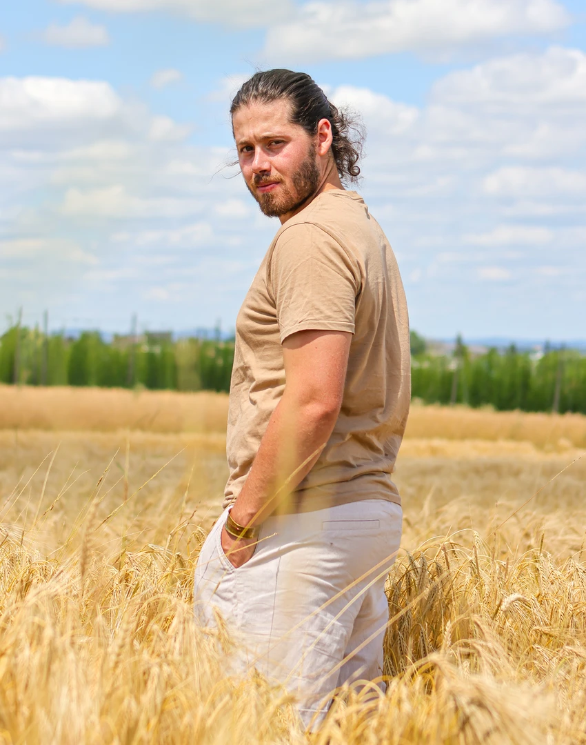 Shooting portrait à Strasbourg et en Alsace - un homme prend position dans un champ de la région, sa tenue vestimentaire s'allie parfaitement aux couleurs naturelles du décor.